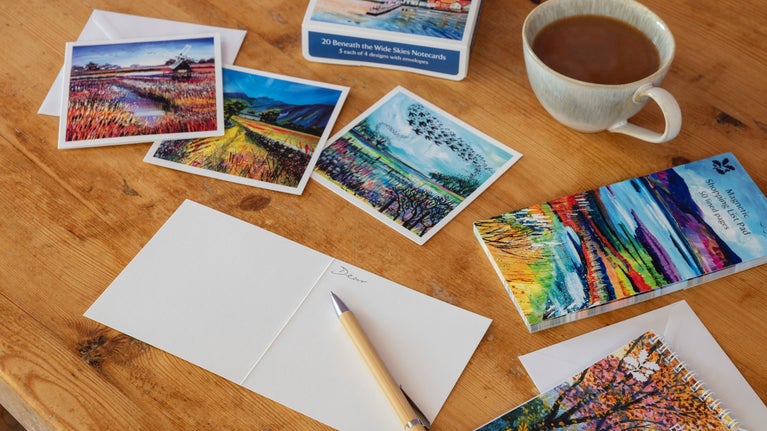 A selection of stationery including notecards and a shopping list pad on a desk.
